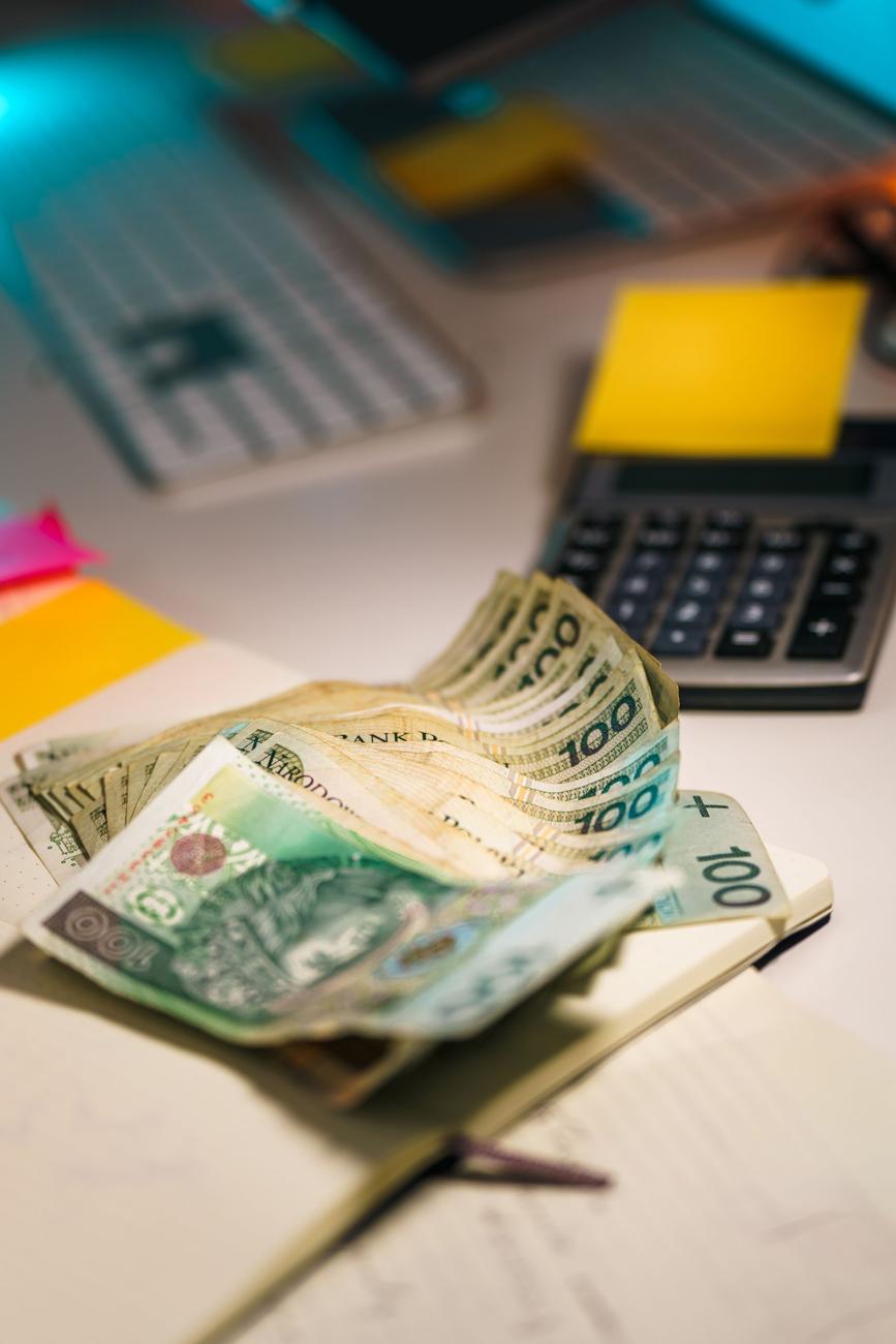 Banknoty, kalkulator i karteczki na biurku
