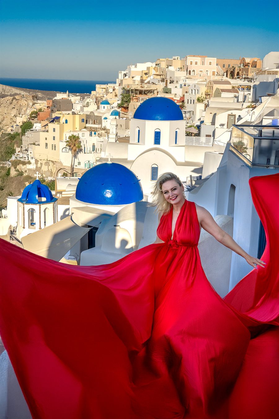 Agnieszka Wójtowicz w czerwonej sukni na tle Oia na Santorini - radość i lekkość w relacjach